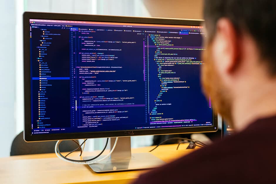 An over the shoulder view of Aaron, one of our developers, who is coding on a large desktop monitor.